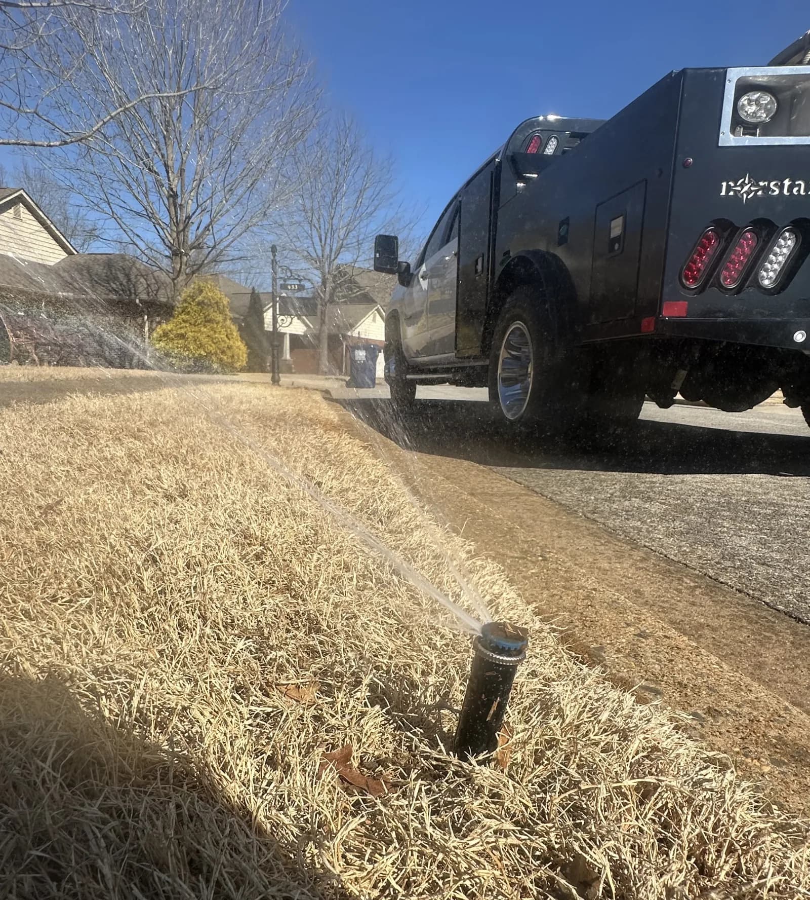 Sprinkler system running beside a driveway during a Huntsville irrigation service visit